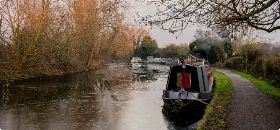 Black canal boat moored on side of canal with other boats